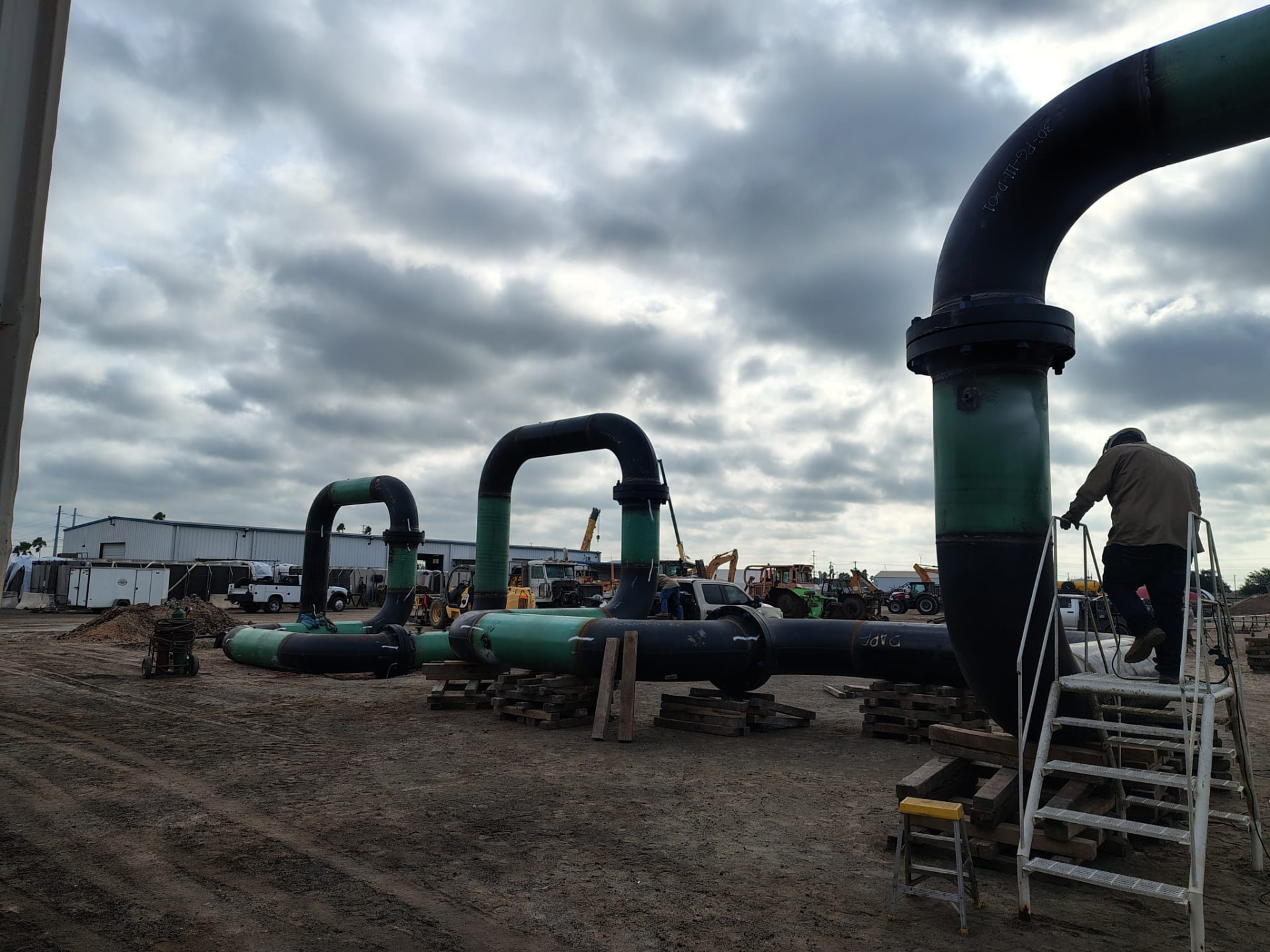 Row of fabricated large-diameter pipe loops staged on cribbing